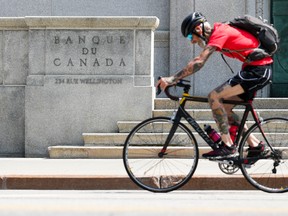 A cyclist makes their way past the Bank of Canada in Ottawa on Tuesday, July 11, 2023.