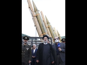 FILE - In this photo released by the Iranian Presidency Office, President Ebrahim Raisi, center, attends a ceremony to deliver the domestically built missiles to the armed forces as his Defense Minister Mohammad Reza Gharaei Ashtiani, left, Iran, on Aug. 22, 2023. Britain, France and Germany announced Thursday Sept. 14, 2023 they will keep their sanctions on Iran related to the Mideast country's atomic program and its development of ballistic missiles. (Iranian Presidency Office, via AP, File)