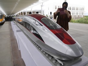 FILE - A woman to take photos of a model high-speed train at the Jakarta-Bandung Fast Railway station in Tegalluar, West Java, Indonesia, Thursday, Oct. 13, 2022. Chinese Premier Li Qiang has taken a test ride on Southeast Asia's first high-speed railway, which connects two Indonesian cities as part of China's Belt and Road infrastructure initiative. Li is visiting Jakarta for two days of talks with leaders of the Association of Southeast Asia Nations and other countries.