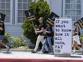 FILE - Picketers carry signs outside Amazon Studios in Culver City, Calif. on Monday, July 17, 2023. A tentative agreement between striking screenwriters and Hollywood studios offers some hope that the industry's dual strikes may be over soon.