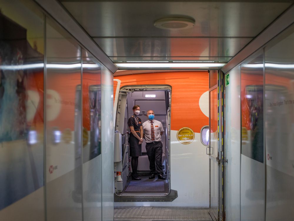 Cabin crew welcome passengers on board a flight, operated by EasyJet, at London Gatwick Airport, in 2020.