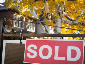 Sold sign on house with autumn leaves in background