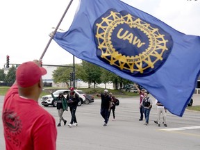 Members of the United Auto Worker Union walk out of the Chicago Ford Assembly Plant as Lance Williams from Lansing, Ill., waves the UAW flag Friday, Sept. 29, 2023, in Chicago.