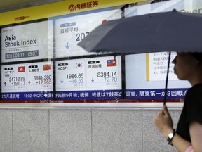 A pedestrian walks past an electronic stock board outside a securities firm in Tokyo, Japan.
