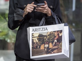 A woman holding an Aritzia Inc. shopping bag on Toronto’s Bloor Street West.