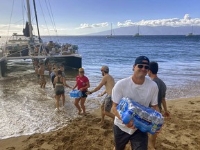 FILE - A group of volunteers who sailed from Maalaea Bay, Maui, form an assembly line on Kaanapali Beach, Saturday Aug. 12, 2023, to unload donations from a boat, after a deadly wildfire destroyed hundreds of homes and left scores of people homeless. It's a transaction that would be commonplace for a corporation or a sports team, but it's the kind of deal that is practically unheard of in the nonprofit sector. The philanthropy research organization Candid will send control of its CF Insights website and the staff that gathered information about community foundations to the Council on Foundations, the association of nearly 900 nonprofit members.