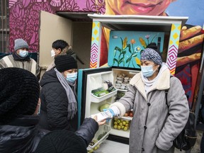 FILE - Volunteers pass out information on the COVID-19 vaccine as people receive food from the 24-hour community fridge at the community center Mixteca during the coronavirus pandemic, Feb. 13, 2021, in the Brooklyn borough of New York. The share of Latinos who give to established charities has dropped sharply since 2008, a new study has found. The same has been true for other Americans, but the percentage of Hispanics who give to help people in need through less formal efforts is higher than for others in the United States.