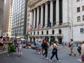 People walk outside the New York Stock Exchange. North American markets opened in the red on Monday.