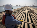 An employee looks out over oil transport pipelines on the Arabian Sea in Saudi Aramco's Ras Tanura oil refinery and oil terminal in Ras Tanura, Saudi Arabia. 