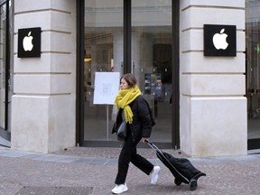 FILE - A woman walks past a closed Apple Store in Lille, northern France, Monday, March 16, 2020. A French watchdog ordered Apple to withdraw the iPhone 12 from the market because it is emitting too high levels of electromagnetic radiation. The National Frequencies Agency (ANFR), the body monitoring public exposure to radiations, called on Apple to "implement all available means to rapidly fix this malfunction," in a statement released on Tuesday Sept.12, 2023.