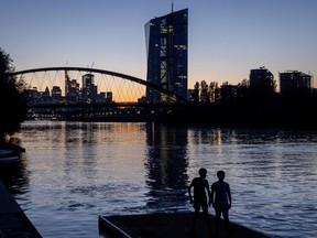 Two boys stand at the river Main near the European Central Bank in Frankfurt, Germany, after sunset on Friday, Sept. 8, 2023.