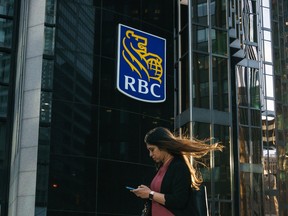 A woman passes Royal Bank of Canada signage in Toronto's financial district.