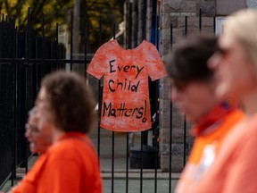 A sign of an orange shirt is attached to a fence during a Truth and Reconciliation walk in Saskatoon, Sask., on Friday, September 30, 2022.