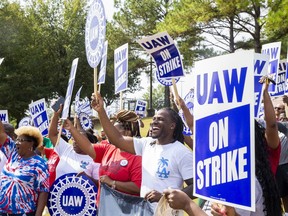 Striking United Auto Workers members cheer and wave their signs