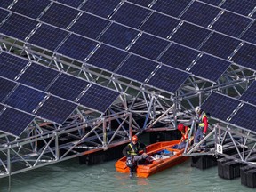 FILE - Workers assemble floating barges with solar panels on the 'Lac des Toules', an alpine reservoir lake, in Bourg-Saint-Pierre, Switzerland, Tuesday, Oct. 8, 2019. Voters in a southern Swiss region cast their ballots Sunday, Sept. 10 2023, to decide whether to allow large solar parks on their sun-baked Alpine mountainsides as part of the federal government's push to develop renewable energies.