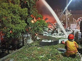 In this image provided by the Pingtung County Government, a firefighter tries to extinguish a fire at a factory of golf ball manufacturer Launch Technologies Co. in the southern county of Pingtung in Taiwan on Friday, Sept. 22, 2023. The factory fire has left multiple people killed, and the victims include several firefighters, according to Taiwanese media reports. (Pingtung County Government via AP)
