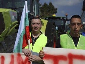 Farmers hold a Bulgarian flag during a protest in the town of Pernik, Monday, Sept. 18, 2023. Farmers in Bulgaria blocked major roads and border crossings nationwide on Monday to protest against their government's decision to lift a ban on imports of food products from Ukraine, complaining that products from the war-torn country will cause an influx and distort local prices.