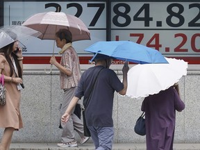 People walk in the rain in front of an electronic stock board showing Japan's Nikkei 225 index at a securities firm Monday, Sept. 4, 2023, in Tokyo. Stocks were higher in Asia on Monday after Wall Street was boosted by a report that signaled the US jobs market, while still healthy, is showing some signs of cooling.