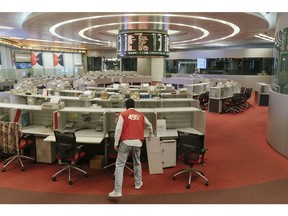 A trader wearing a red trading jacket cleans up a booth on the trading floor of the Hong Kong Stock Exchange, operated by Hong Kong Exchanges & Clearing Ltd. (HKEX), in Hong Kong, China, on Tuesday, Oct. 24, 2017. HKEX will shut its iconic Trading Hall on Oct. 27, 31 years after opening the space in the heart of the city's financial district. Photographer: Anthony Kwan/Bloomberg