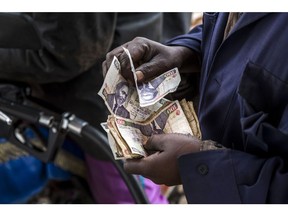 A petrol station worker fills counts Kenyan Shillings notes after being paid by a costumer at Euro Petroleum petrol station located in Baba Dogo suburb, Nairobi, Kenya on Wednesday, March 28th, 2018. Heavy taxes raise Kenya's petrol prices. Photographer: Luis Tato/Bloomberg