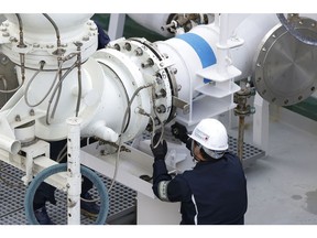 A worker connects a liquefied natural gas (LNG) transfer pipe, left, to the LNG tanker Sohshu Maru, berthed at Jera Co.'s Futtsu Thermal Power Station in Futtsu, Chiba Prefecture, Japan, on Friday, Dec. 17, 2021. North Asia spot LNG prices hovered near $40/mmbtu, with buyers in the region satisfied by inventory levels heading into winter, while European prices traded at a premium to Asian values for a third day. Photographer: Kiyoshi Ota/Bloomberg