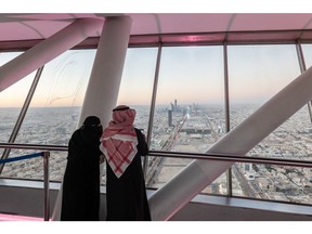 Visitors looks out towards the city skyline from the skybridge of the Kingdom Center, in Riyadh, Saudi Arabia, on Thursday, Jan. 19, 2023. Mostly shut off to foreign visitors for years, Crown Prince and de facto ruler Mohammed bin Salman has unveiled an ambitious push to use tourism as a way to help diversify the oil-dependent economy.