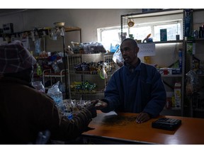 A shop owner gives change to a customer in a mini-market, during a period of loadshedding, in the township of Namahadi, Frankfort, South Africa, on Saturday, June 3, 2023. The rural town of Frankfort has returned into scheduled blackouts, following a court-issued ban sought by Eskom Holdings SOC Ltd. against Rural Free State (Pty) Ltd., who were easing loadshedding schedules for residents by providing power from a local photovoltaic solar plant.