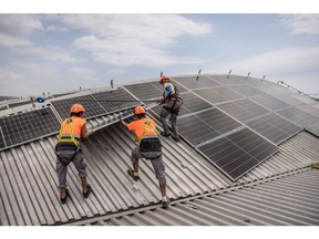 Workers place a solar panel onto the roof of a Barcelona Metro workshop building, the Generalitat of Catalonia's largest solar power project, in the Zona Franca industrial area of Barcelona, Spain, on Friday, July 21, 2023. Spain is on track to become the first country among Europe's big five economies to generate more than 50% of its electricity from renewable sources, according to a forecast by Rystad Energy.