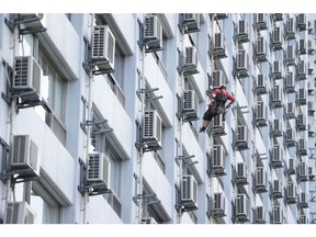 A worker washes windows next to air conditioning units at an apartment building in Tokyo, Japan, on Friday, July 21, 2023. Temperatures in central Tokyo have soared to nearly 9C (16F) above the seasonal average, as the extreme heat blanketing the world continues to smash historical norms. Photographer: Toru Hanai/Bloomberg