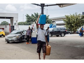 A customer carries containers of fuel from a gas station in Lagos, Nigeria, on Wednesday, Aug. 23, 2023. Gasoline prices have more than tripled since the subsidies were abolished on May 29, exacerbating a cost-of-living crisis in Africa's biggest economy.