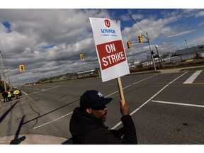 An "On Strike" sign held on a picket line outside General Motors Canada's Oshawa Assembly Complex in Oshawa, Ontario, Canada, on Tuesday, Oct. 10, 2023. General Motors Co. reached a tentative agreement with its Canadian union, Unifor, ending a strike that had halted work at three plants in Ontario about 13 hours after it began. Photographer: Cole Burston/Bloomberg