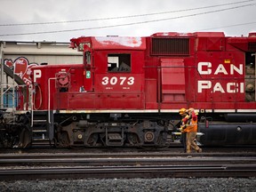 CP Rail employees walk past locomotives in the Alyth yards in Calgary.
