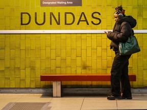 A woman uses her phone while waiting on a subway platform in Toronto.