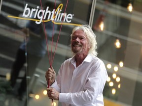 FILE - Richard Branson, of Virgin Group, prepares to unfurl a banner during a naming ceremony for the Brightline train station, to be renamed as Virgin MiamiCentral in Miami on April 4, 2019. A British judge ruled in favor of Richard Branson's Virgin group on Thursday Oct. 12, 2023 in its lawsuit against a U.S. train company that terminated a licensing agreement and claimed the Virgin brand was no longer one of "high repute."