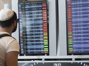 Passengers look at the monitor displaying delayed flights at Ben Gurion airport, near Tel Aviv, Israel, Monday, March 27, 2023.