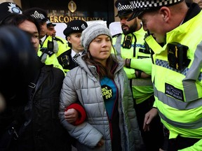 A police officer speaks to Swedish climate activist Greta Thunberg moments before being arrested outside the InterContinental London Park Lane.