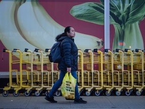 A pedestrian walks past a store in Toronto with a bag of groceries. Statistics Canada released inflation data for September this morning.
