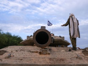 An Israeli soldier wearing a prayer shawl stands on top of a tank positioned in the western Galilee area, near Israel's northern border with Lebanon on Oct. 30.