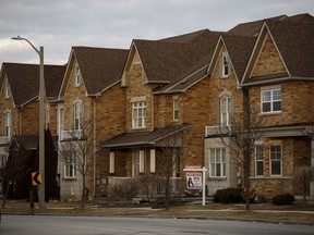 A 'For Sale' sign in front of a row of homes in a subdivision in Vaughan, Ont.