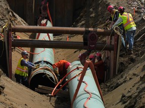 Workers place pipes during construction of the Trans Mountain pipeline expansion on farmland in Abbotsford, B.C.