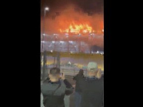 This image taken from video provided by Molly Bullard, shows a fire that broke out in one of the parking lots at Luton Airport, in Luton, England, Tuesday, Oct. 10, 2023. Luton Airport, located about 35 miles (56 kilometers) north of central London, said that "all flights are currently suspended as emergency services respond to a car fire that has spread in Terminal Car Park 2."