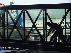 FILE - A worker cleans a jet bridge at Paine Field in Everett, Wash., before passengers board an Alaska Airlines flight on March 4, 2019. Seattle-based Alaska Airlines owns Horizon Air. An off-duty pilot riding in the extra seat in the cockpit of a Horizon Air passenger jet on Sunday, Oct. 22, 2023, tried to shut down the engines in mid-flight and had to be subdued by the crew, according to a pilot flying the plane.