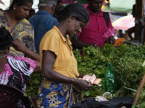 FILE- A vendor counts currency notes as she sells vegetables at a market place in Colombo, Sri Lanka, June. 1, 2023. Sri Lanka has reached an agreement with the Exim Bank of China on key terms and principles for restructuring its debt, a key step toward unlocking a second instalment of a $2.9 billion package from International Monetary Fund aimed at rescuing the island nation from a dire economic crisis.