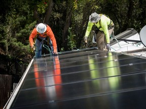 Des employés installent des panneaux solaires sur le toit d'une maison en Californie.