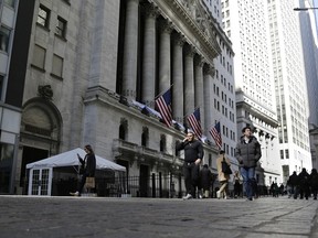 People pass in front of the New York Stock Exchange. North American stocks opened in the red on Monday.