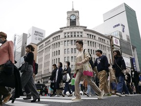 FILE - People walk across a pedestrian crossing in Ginza shopping district on March 31, 2023, in Tokyo. Business sentiment among big Japanese manufacturers improved in July-September for the second straight quarter, according to a central bank survey released Monday, Oct 2.
