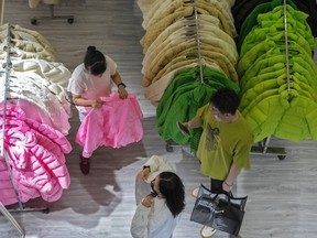 FILE - A woman tries out a fall outfit at a booth doing a promotion sale on clothing for the upcoming autumn season at a shopping mall in Beijing, Sunday, Aug. 20, 2023. China's economy remains in the doldrums, data released Friday, Oct. 13, showed, with prices falling due to slack demand from consumers and businesses.
