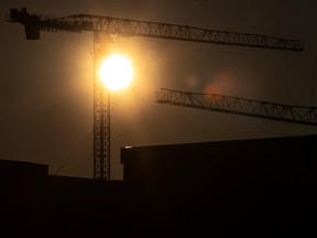 The sun sets behind construction cranes in Toronto.
