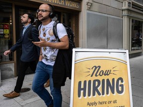 People walk past a restaurant, with a hiring sign outside, in Washington, D.C.