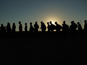 FILE - Migrants who crossed the Rio Grande and entered the U.S. from Mexico are lined up for processing by U.S. Customs and Border Protection, Sept. 23, 2023, in Eagle Pass, Texas. The Biden administration is expected to keep the cap on refugees admitted into the country at 125,000 for the next fiscal year, which starts Sunday.